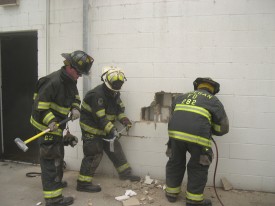 Firefighters are shown utilizing various tools while wearing full PPE including safety glasses.