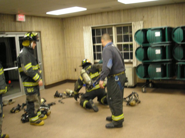 Capt Cerrato Demonstrates On Firefighter Gurdineer How An Airpack Can Get Caught Up In A Fire